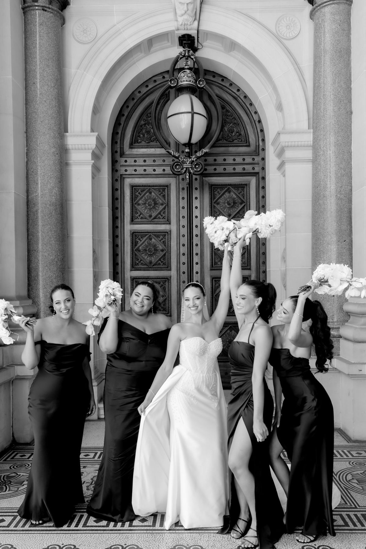Bride and bridesmaids celebrating with bouquets raised