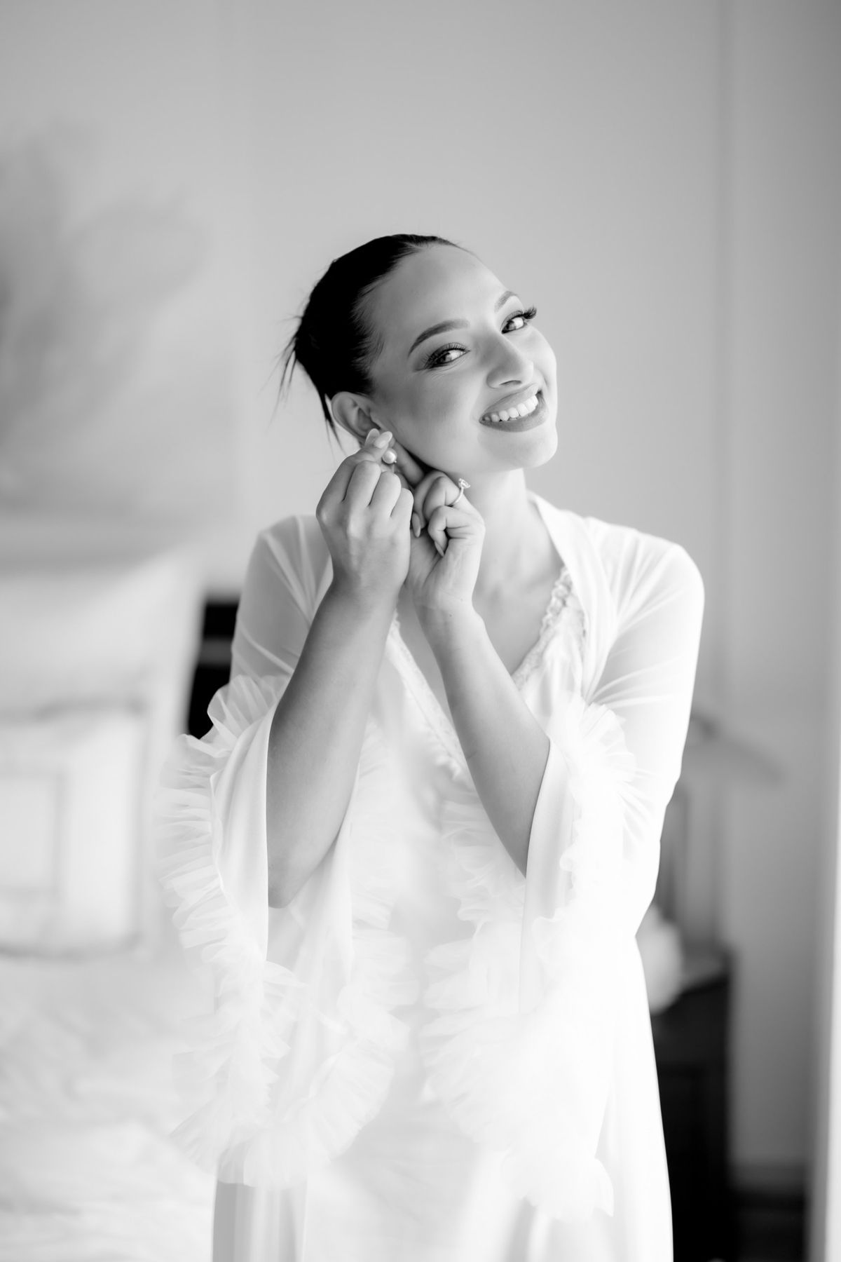 Bride laughing as she puts on her earrings