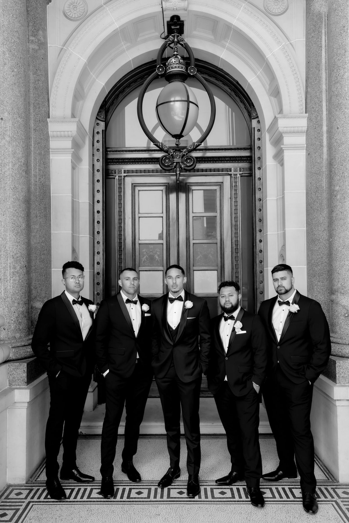 Groom and groomsmen standing under an ornate doorway lantern