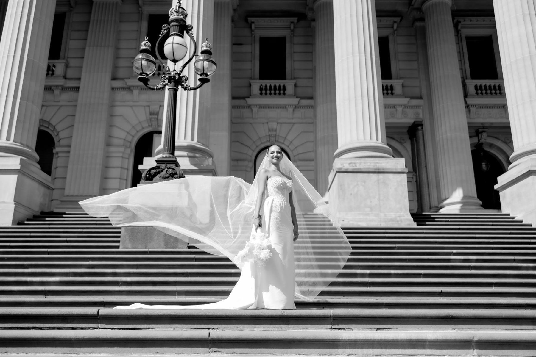 Bride on grand parliament steps as her long veil sweeps out in the wind